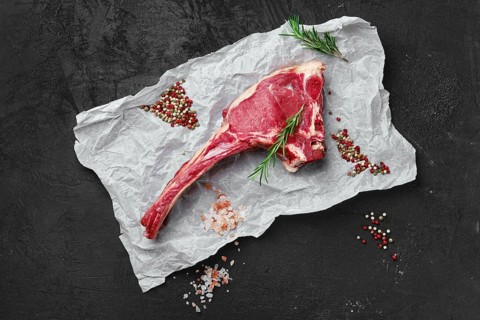 Top view of raw prime ribeye steak on wooden wrapping paper