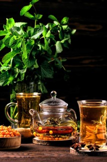 Low key photo of hot herbal tea with sea buckthorn and mint on wooden table