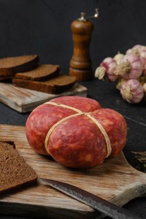 Smoked round beef sausage on cutting board over black background