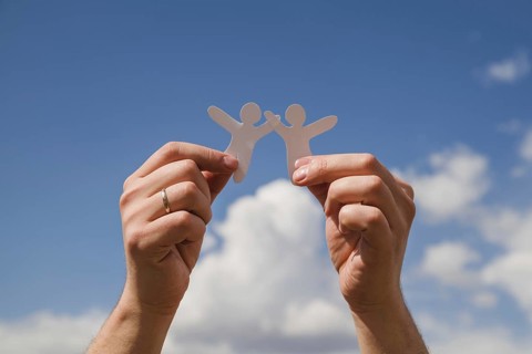 Paper dolls against sky