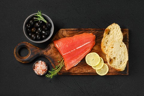 Top view of piece of fresh salmon tail fillet with ciabatta and spicy herb sauce