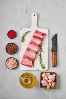 Raw fresh beef short rib stripes on wooden cutting board with spice and herbs for marinade