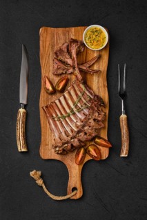 Overhead view of grilled ribs of lamb on a plate with spicy sauce