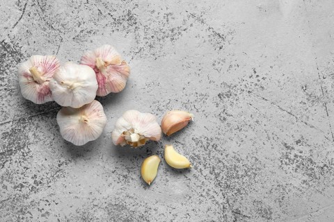 Top view of garlic cloves and bulbs on wooden cutting board