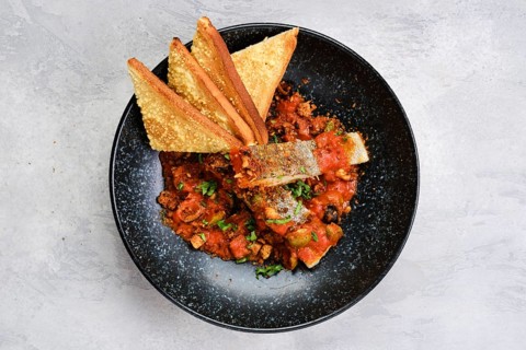 Top view of fried zander served with steamed tomato