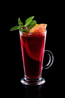 Glass of hot rose tea with grapefruit and mint isoalted on black.