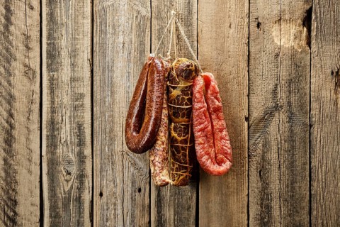 Assortment of dried meat and sausages hanging on a barn wall