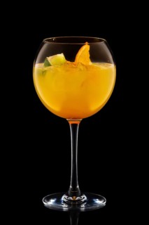 Big round wine glass with fresh cold lemonade isolated on black background