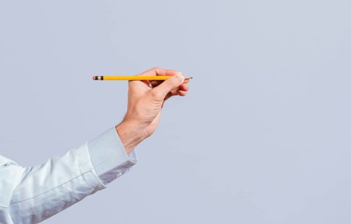 Male hand holding a pencil on a blank. Man fingers holding a pencil with blank space. Person hands holding a pencil on a space for text
