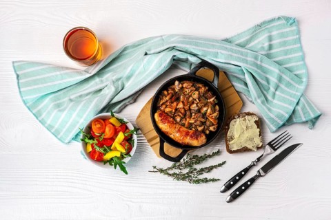 Cast-iron pan with fried sausage and mushrooms