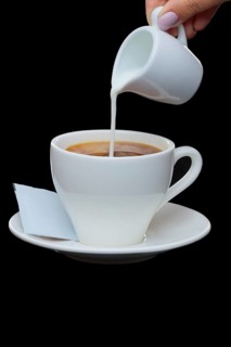 Pouring milk in coffee. Photo with clipping path isolated on black background