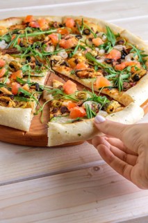 Hand picking slice of pizza with shrimps