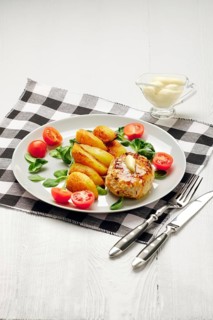 Fried chicken cutlet with potato slices served with tomato cherry and corn salad. Traditional belorussian food