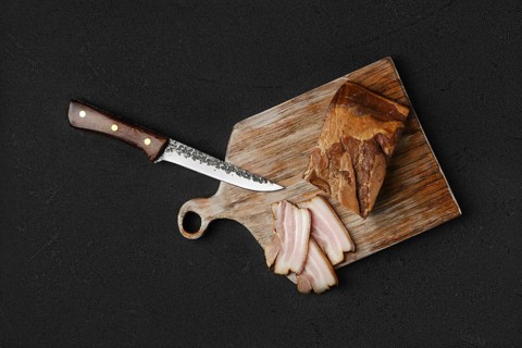 Overhead view of smoked pork bacon with brown bread and eggs on wooden cutting board