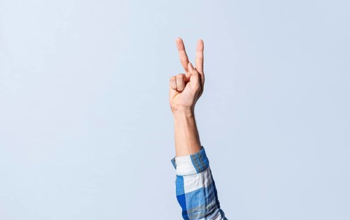 Hand gesturing the letter K in sign language on an isolated background. Man's hand gesturing the letter K of the alphabet isolated. Letters of the alphabet in sign language