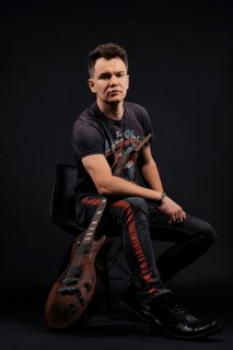 Low key portrait of musician sitting on chair with electro guitar