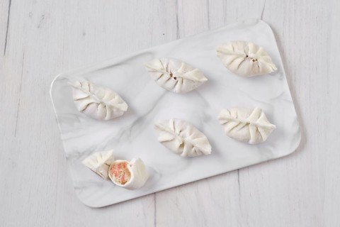 Top view of frozen dumplings stuffed with liver and provencal herbs on marble serving plate