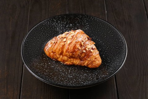Freshly baked big croissant with caramel on a plate