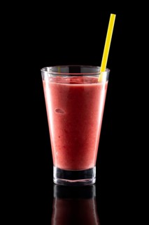 Glass of fresh cold smoothies with straw isolated on black background