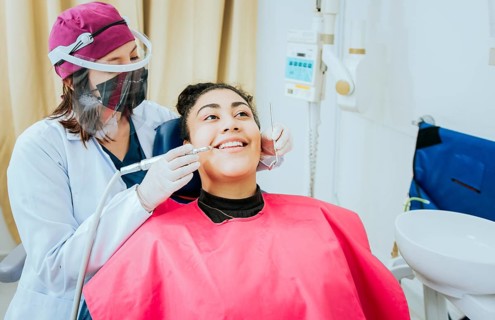 Female dentist cleaning a patient mouth with a drill. Close-up of a stomatologist cleaning a woman teeth