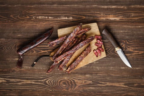 Air dried homemade beaver sausages on wooden background