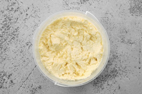 Top view of homemade processed cheese in plastic bowl