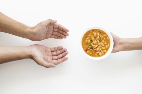 Hand giving soup bowl needy person