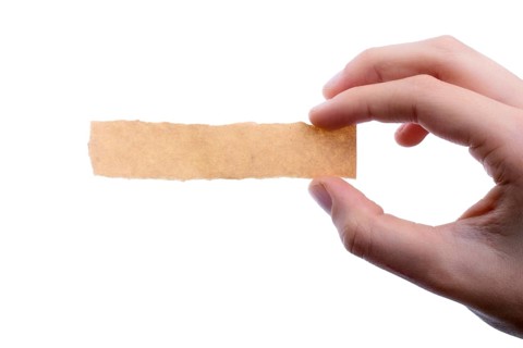 Hand holding a piece of blank torn notepaper