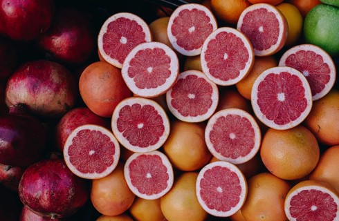 Cut in halves grapfruits alongside pomegranates on display
