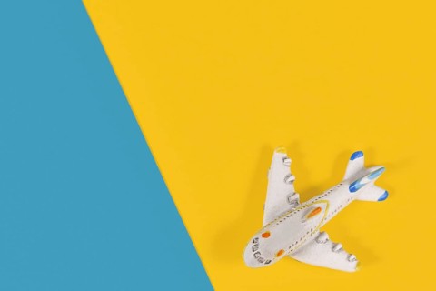 Small model airplane in corner of yellow and blue background