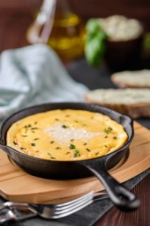 Omelette in cast iron skillet with bread and herbal butter