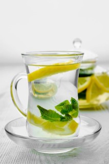 Antioxidant hot drink with lemon and mint in transparent tea pot and glass