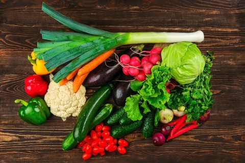 Overhead view of assortment of fresh vegetables on dark wooden background