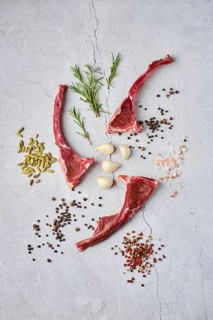Composition with raw doe ribs with spice and herb over concrete background