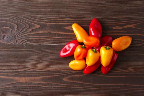 Sweet mini peppers sorted by color natural wooden background