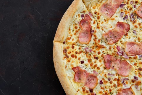 Close up view of pizza carbonara with bacon and onion
