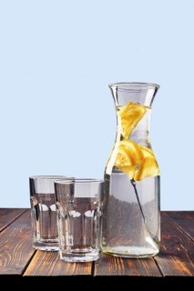 Jug with cold water with ice and lemon and two empty glass on the table with space for inscription