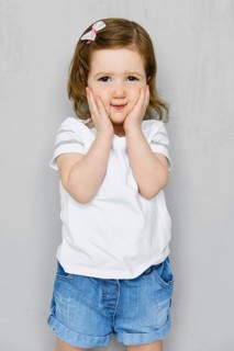 Two years old girl in white t-short and jeans shorts posing in studio