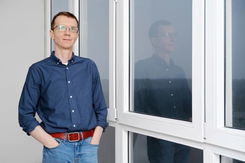 Middle-aged man is standing with hands in pockets on balcony in the early morning