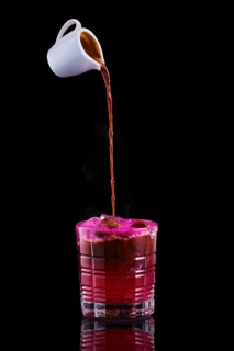 Pouring hot espresso in glass with tonic and dragon fruit syrup isolated on black background