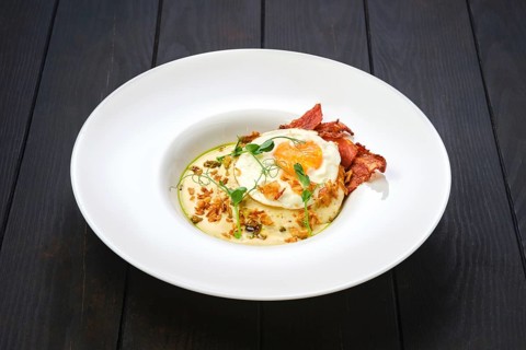 Fried egg with bacon slices and chips served with creamy sauce