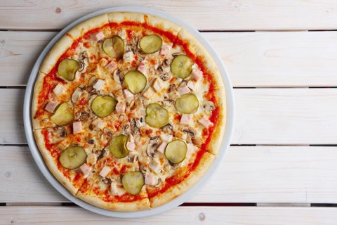 Top view of pizza with ham and pickled cucumber