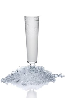 Sling glass with ice-cream and whipped cream on heap of crushed ice isolated on white