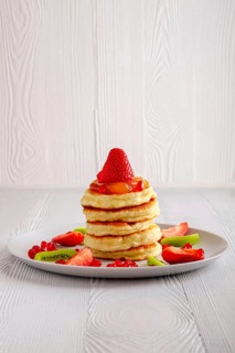 Stack of hot flapjacks served with fresh strawberries and kiwi