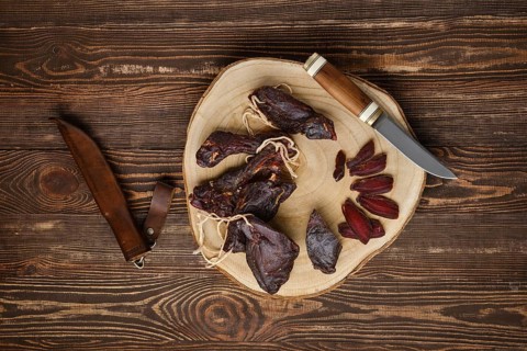 Overhead view of dried jerked deer or venison meat on wooden background