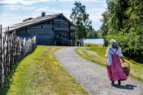 Traditionla dressed woman on her way to a wooden house