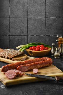 Smoked lamb sausage rings on wooden cutting board on kitchen table