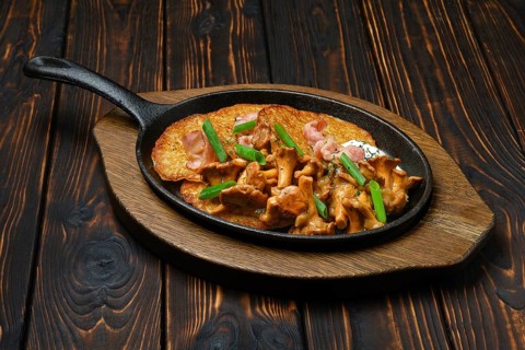 Potato pancakes with chanterelles and pork in cast iron skillet