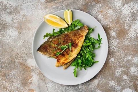 Top view od fried dorada fish with fresh arugula