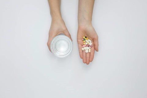 Flat lay hand holding pills glass water